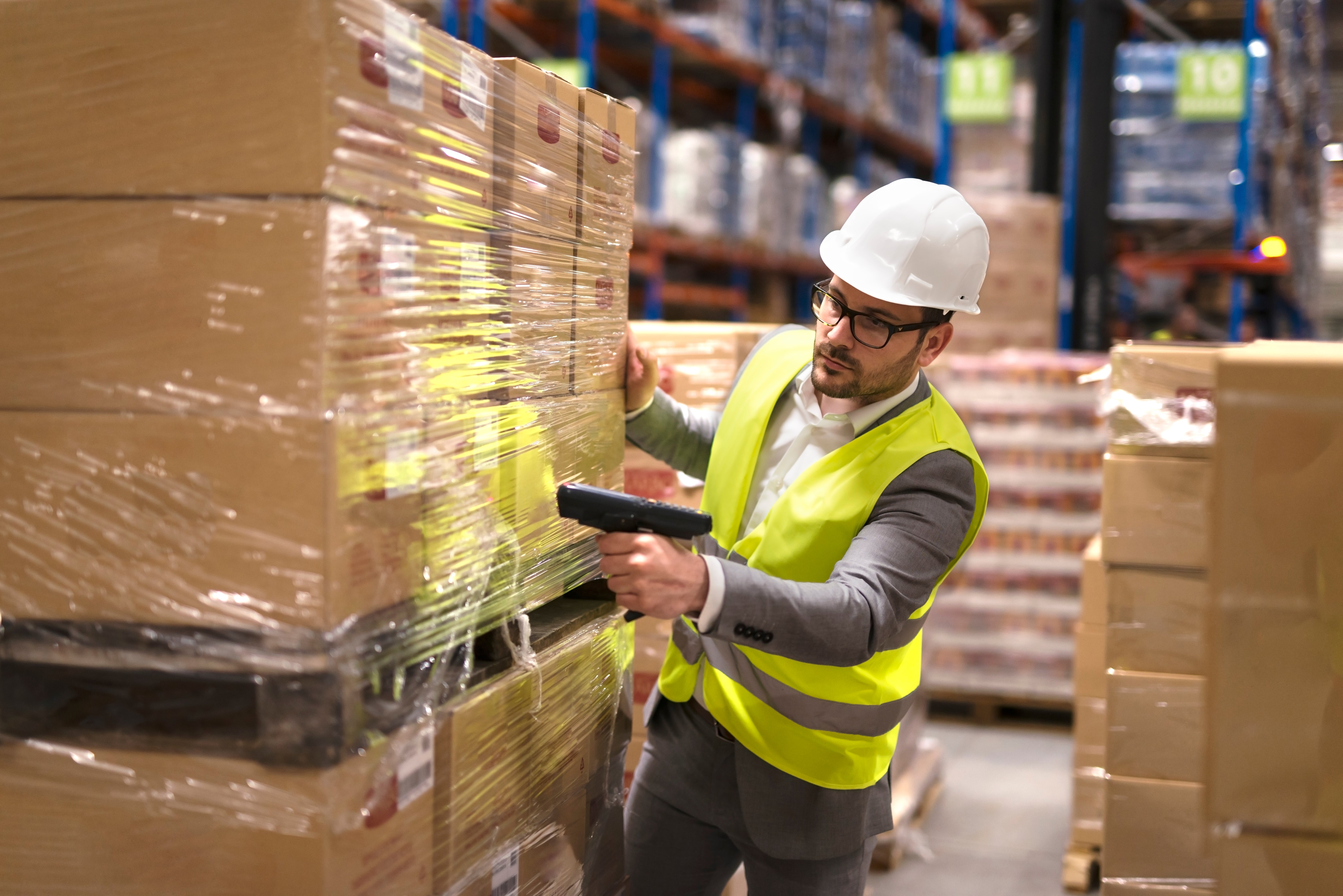 male-warehouse-worker-using-bar-code-scanner-to-analyze-newly-arrived-goods-for-further-placement-in-storage-department